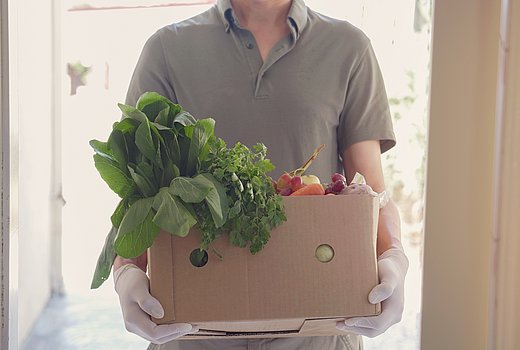 Ein Mann liefert eine volle Kiste mit frischem regionalem Gemüse 