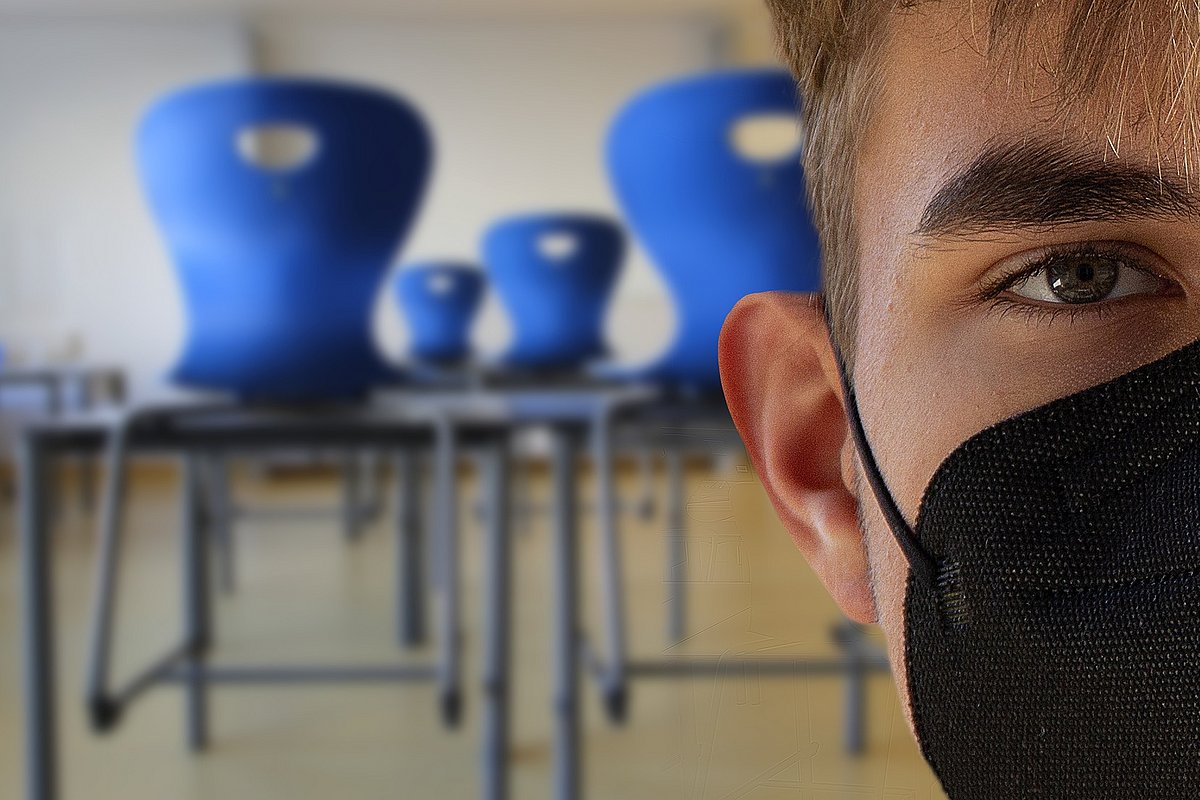 Jugendlicher Schüler mit Maske im Klassenraum