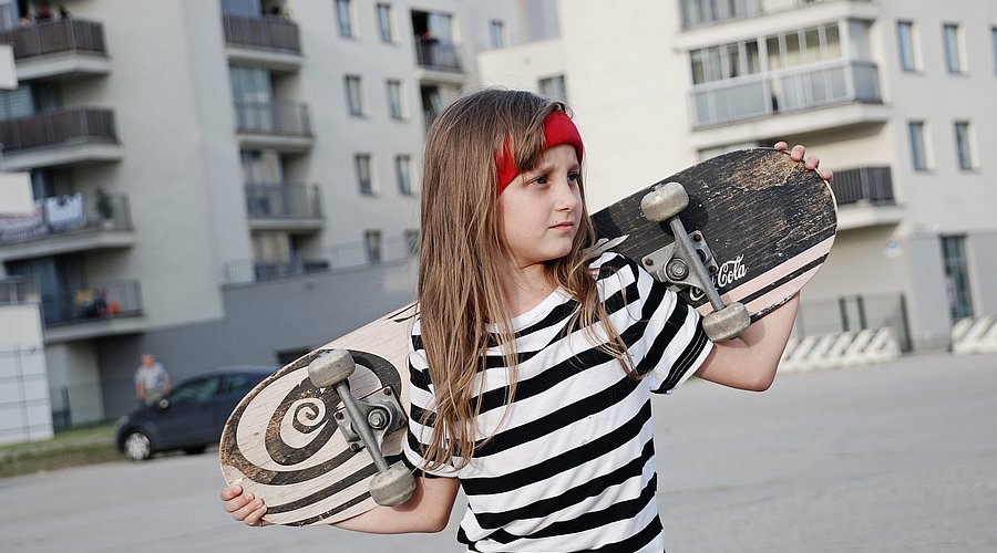 Jugendliches Mädchen mit Skateboard auf der Straße