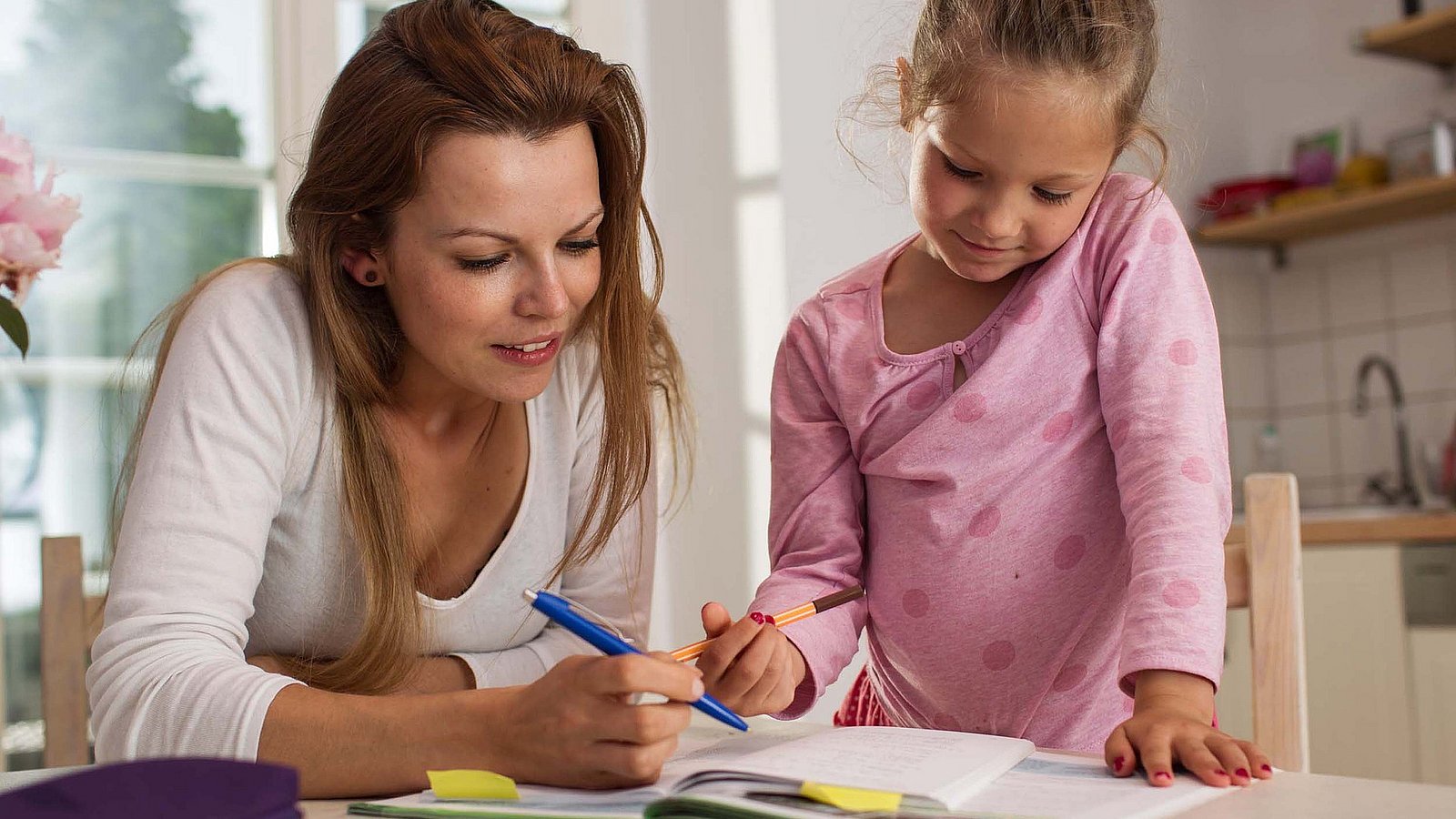 Mädchen macht mit ihrer Mutter Hausaufgaben. 