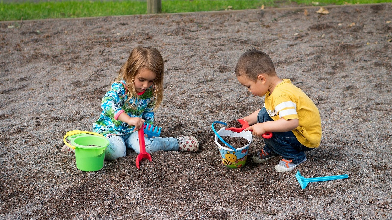 Zwei Kinder spielen im Sandkasten.