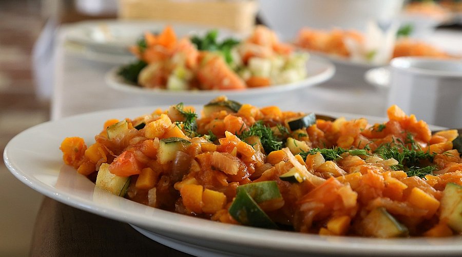 Mit Essen gefüllte Teller auf einem Tisch. Eine Gemüse-Getreide-Mischung.