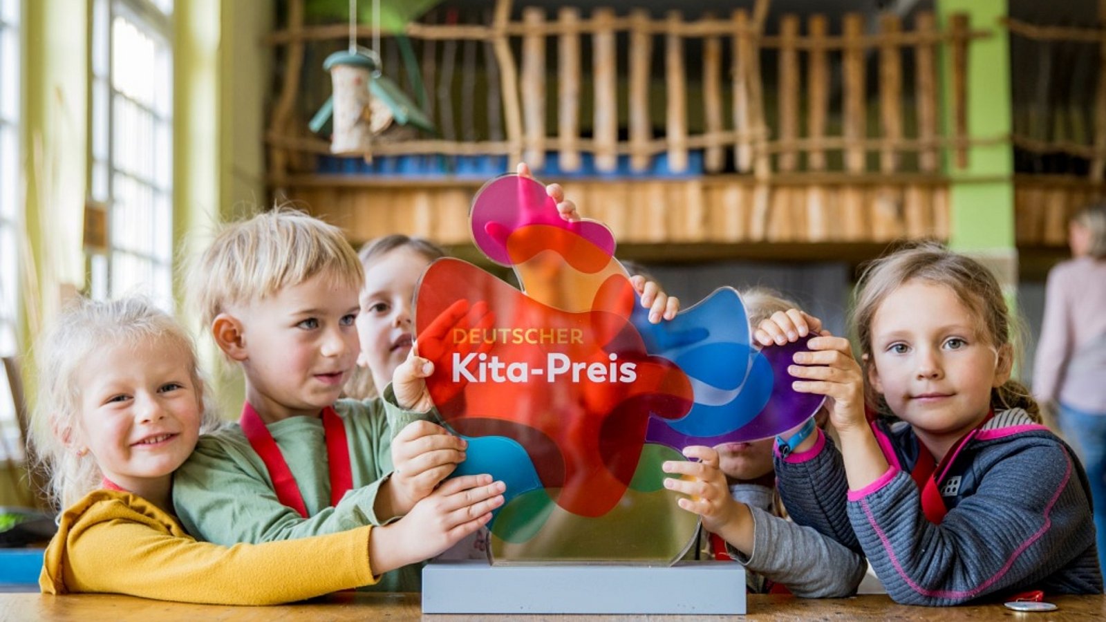 Kita-Kinder zeigen die Trophäe zum Deutschen Kita-Preis 2023