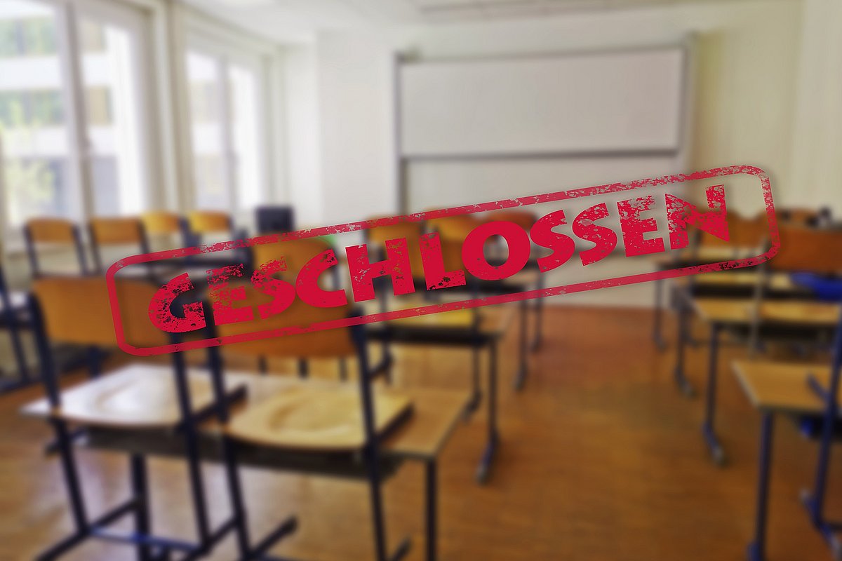 In einem Klassenzimmer sind alle Stühle hochgestellt. Quer über das Bild verläuft ein Banner mit dem Wort "Geschlossen". 