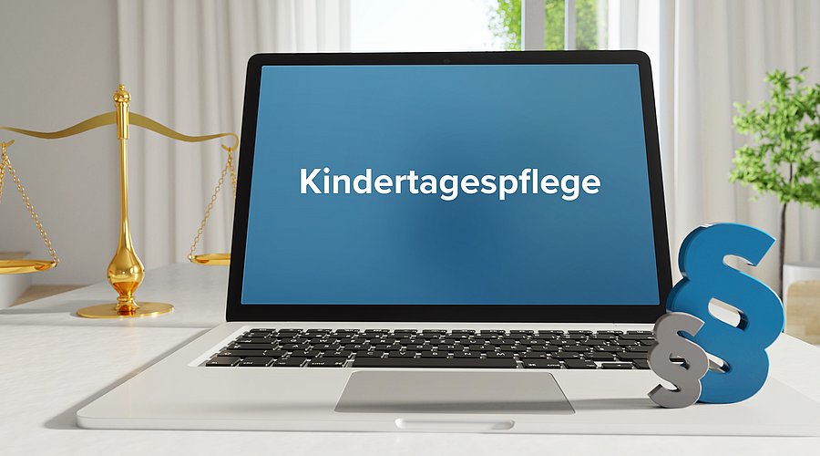 Laptop mit Aufschrift Kindertagespflege neben Paragraphen-Zeichen 