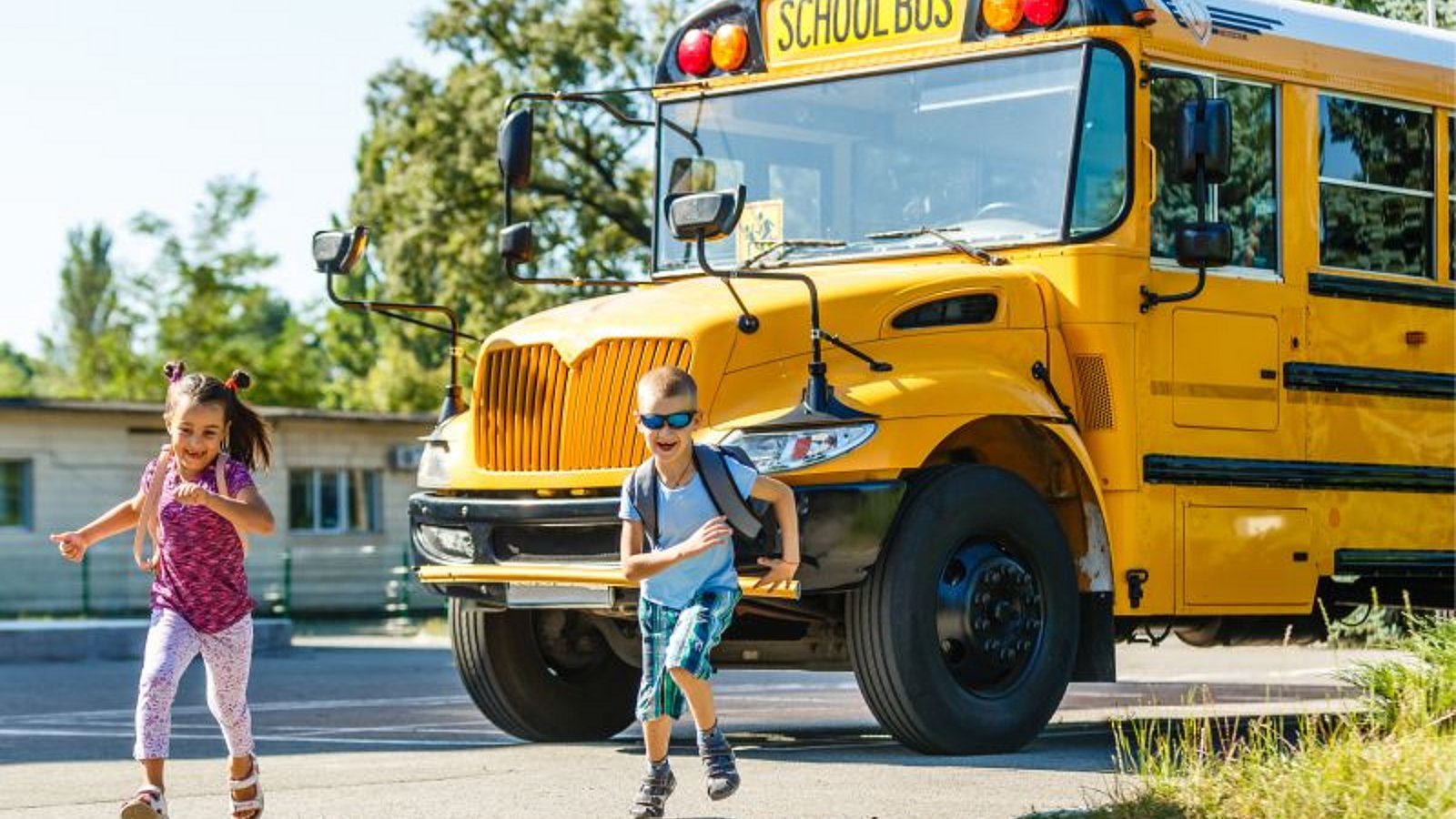 Zwei Schulkinder vor einem US-amerikanischen Schulbus