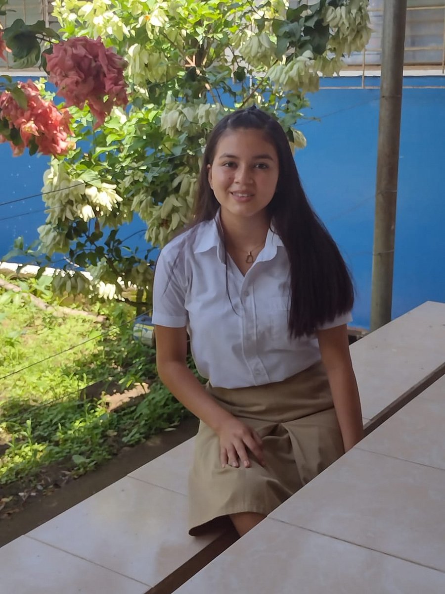 Mädchen sitzt in einem Schulgarten in einer Kommune in El Salvador.