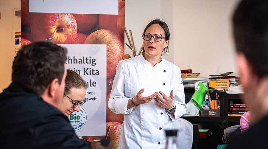 Auf einer Veranstaltung referiert eine Köchin über den Einsatz von Bio-Produkten in der Kita- und Schulverpflegung.