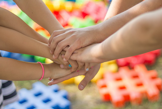 Kinder die ihre Hände als Symbol der Zusammenarbeit übereinander legen 