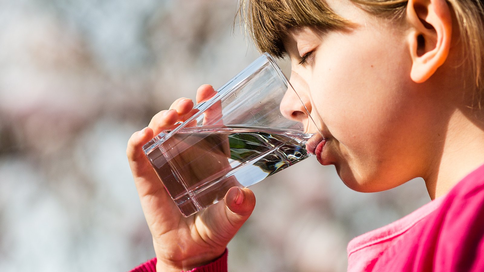 Kind trinkt Wasser aus einem Glas