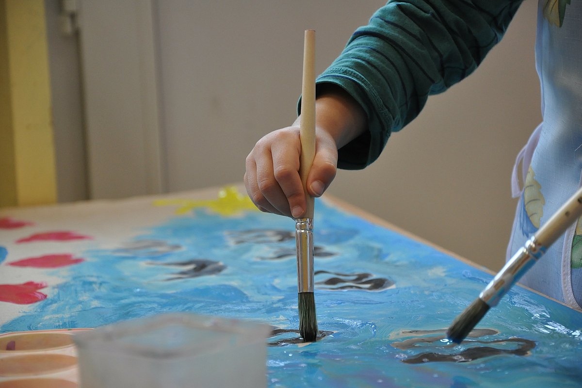 Kind malt mit Wasserfarbe und Pinsel
