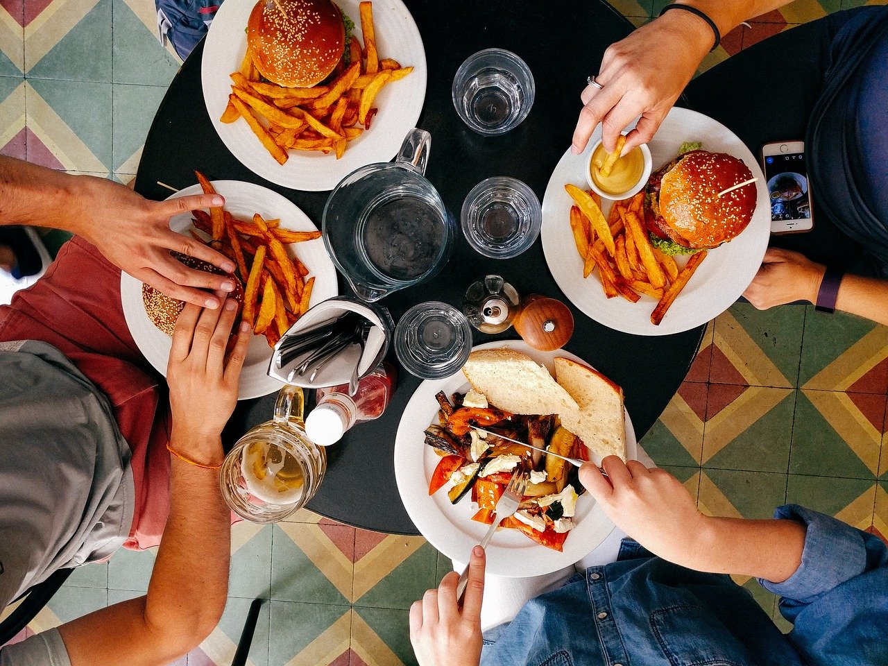Vier Jugendliche sitzen an einem Tisch und essen Fast Food